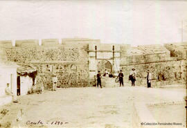 Ceuta, puerta en la muralla con un puente levadizo, con militares de guardia y transeuntes. Fotógrafo desconocido.