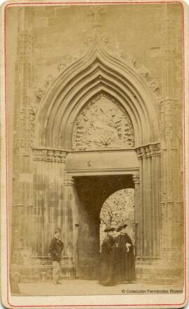 Barcelona, Catedral, puerta de la Piedad de entrada al Claustro desde el exterior con dos sacerdotes con capa y teja y un paisano tocado con una barretina. Rovira y Durán.