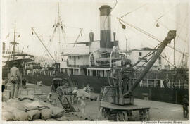 Málaga, barcos amarrados al muelle del puerto y faenas de carga o descarga. Autor desconocido.